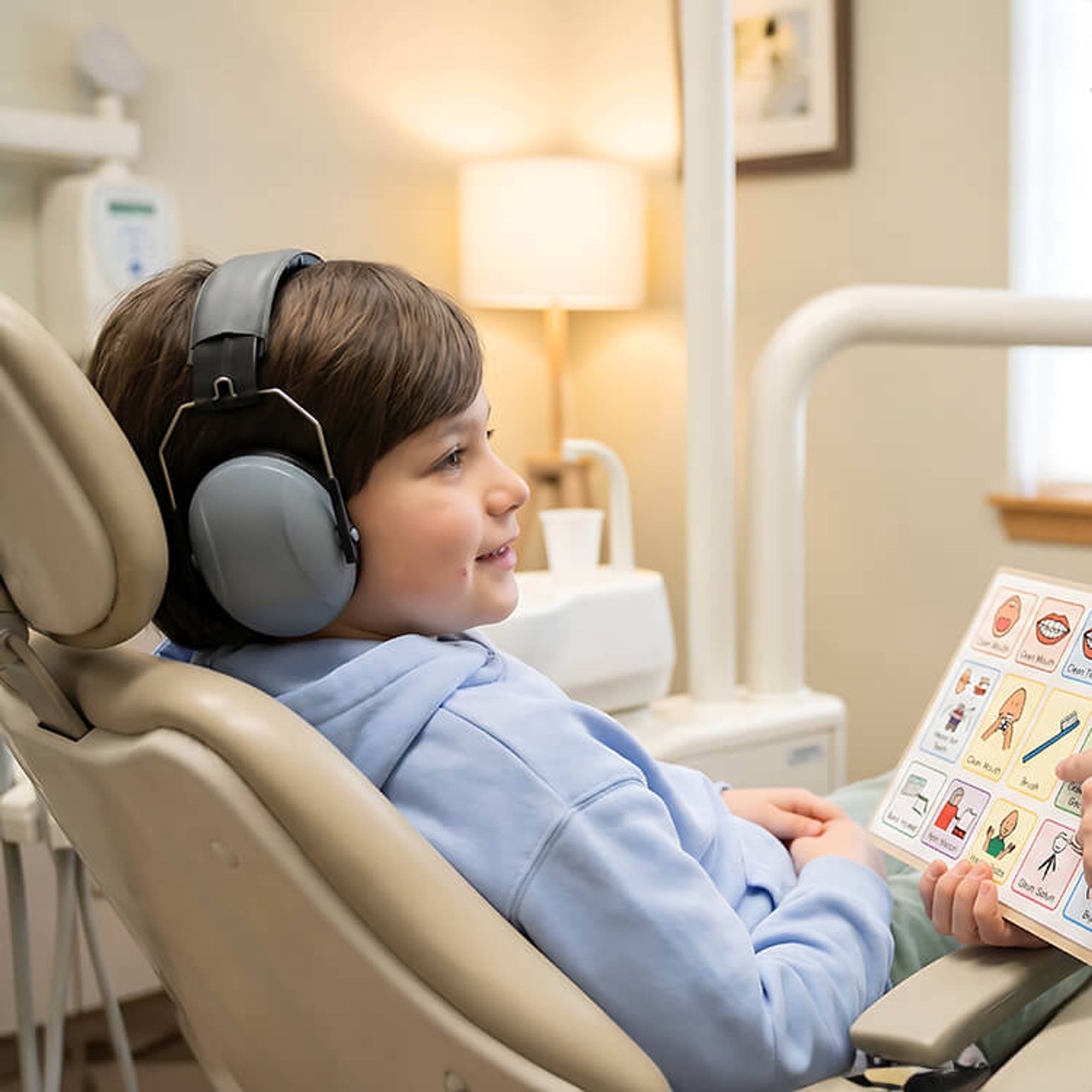 Pediatric Dentist Using Visual Aids and Noise-Canceling Headphones for Child with Sensory Processing Needs During Medical Exam