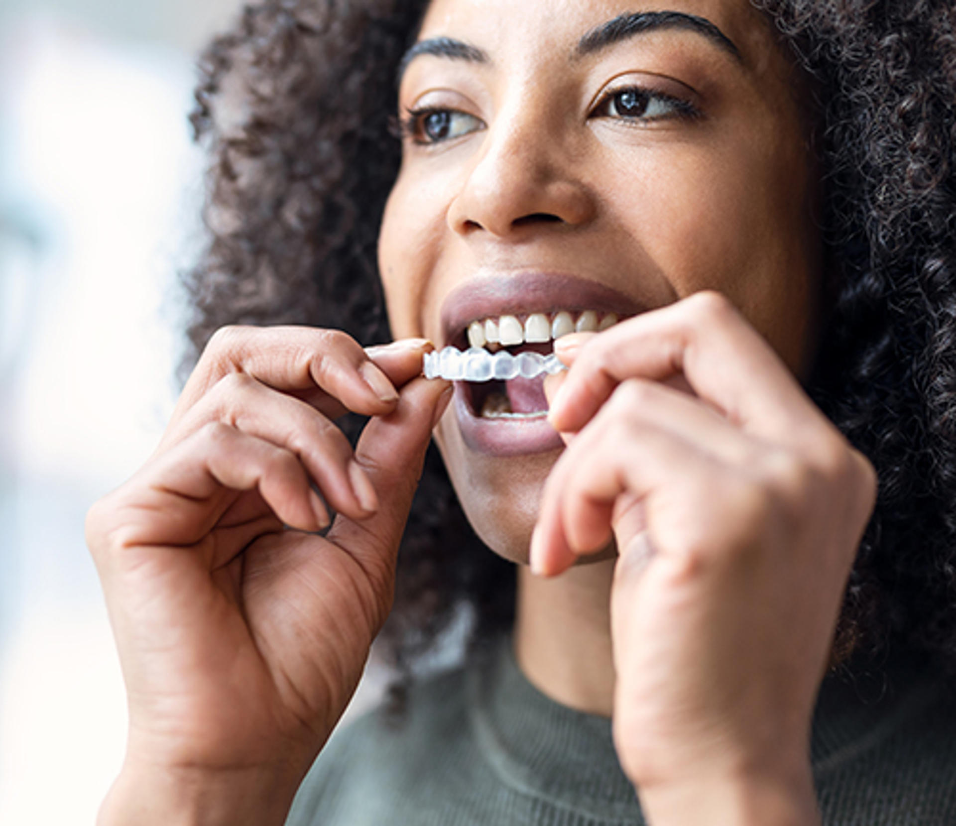 woman putting a clear aligner in her mouth