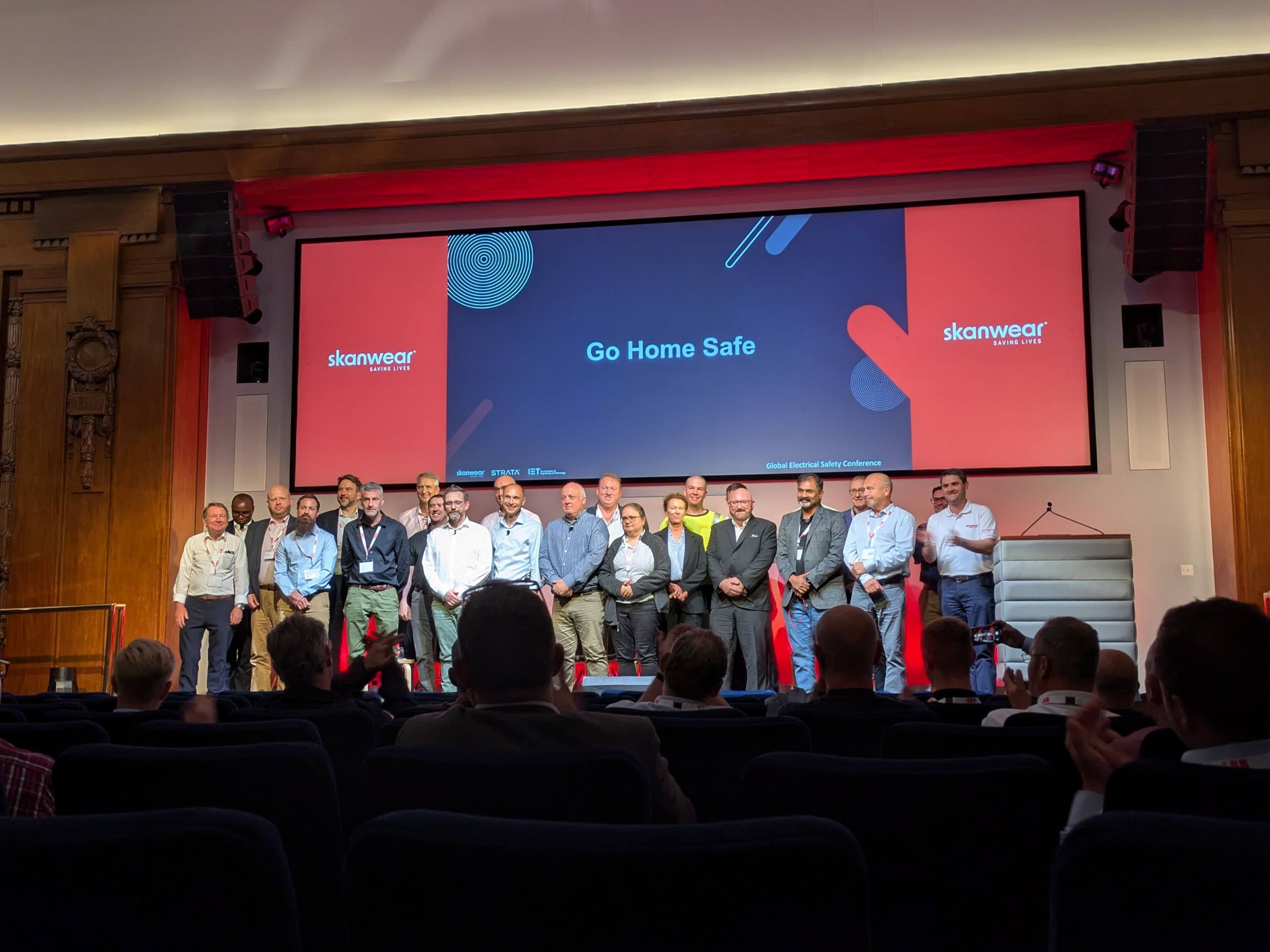 The speakers at the 2024 Global Electrical Safety Conference standing on stage to receive audience applause