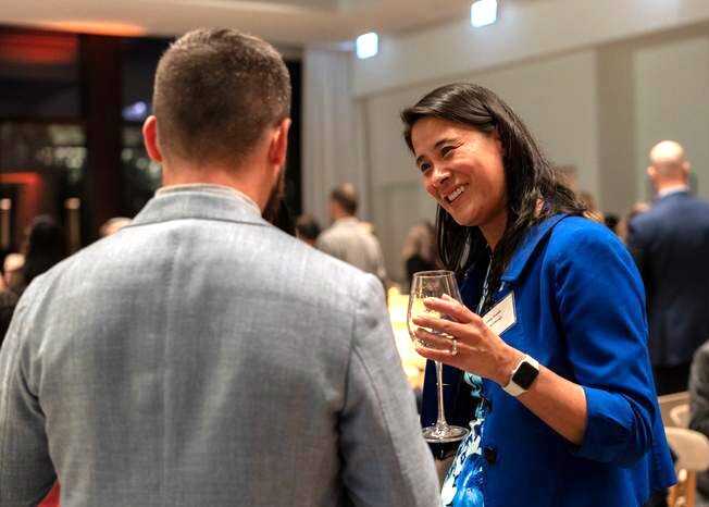 Two people chatting at an event, one is a lady in a blue top