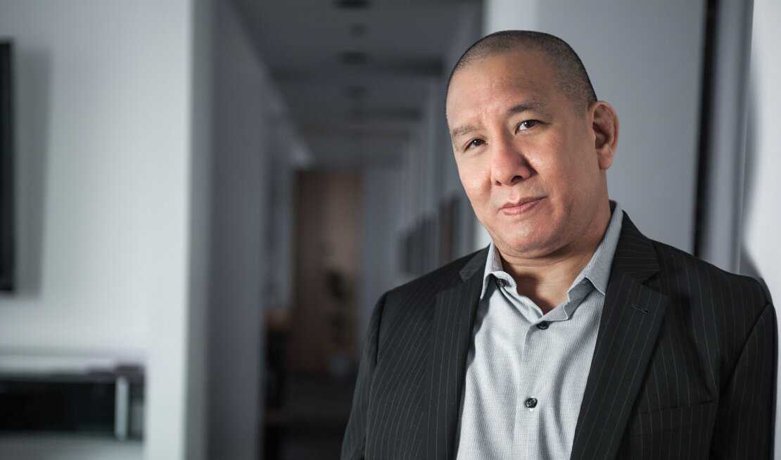 Photo of a man with short hair looking at the camera, he is in focus on the right side of the image.