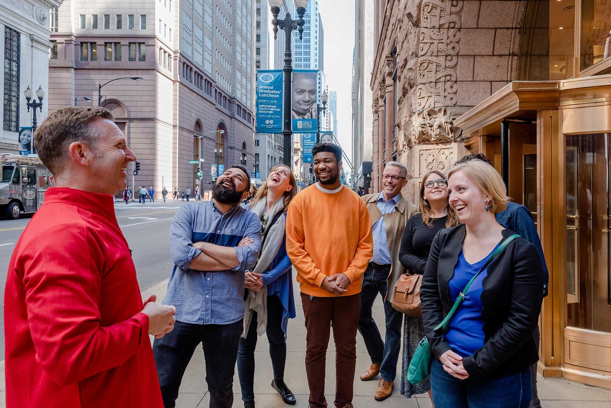 A group of tourists having an engaging interaction with a docent in a red jacket