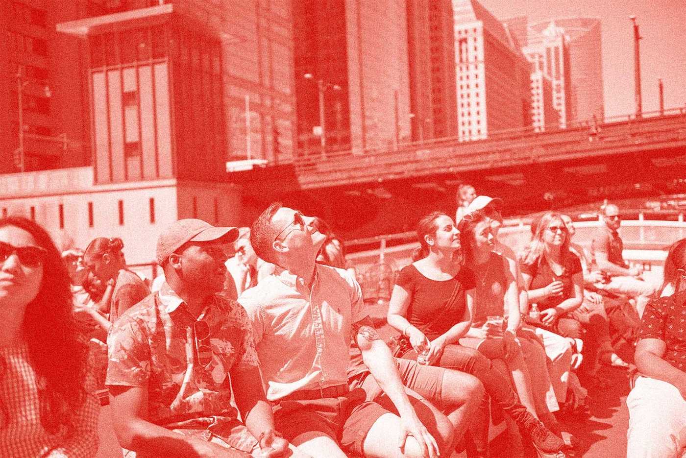 Image of a group looking up at skyscrapers on a river boat tour. The image has a red overlay. 