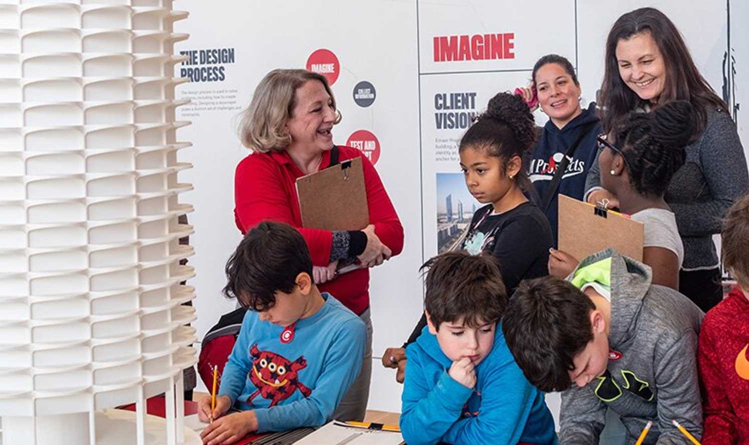 Docent and teacher overlooking young kids with an observed project