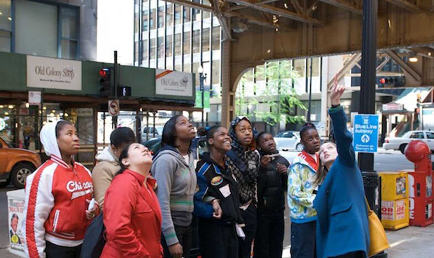 Docent pointing to something while a group of kids look on