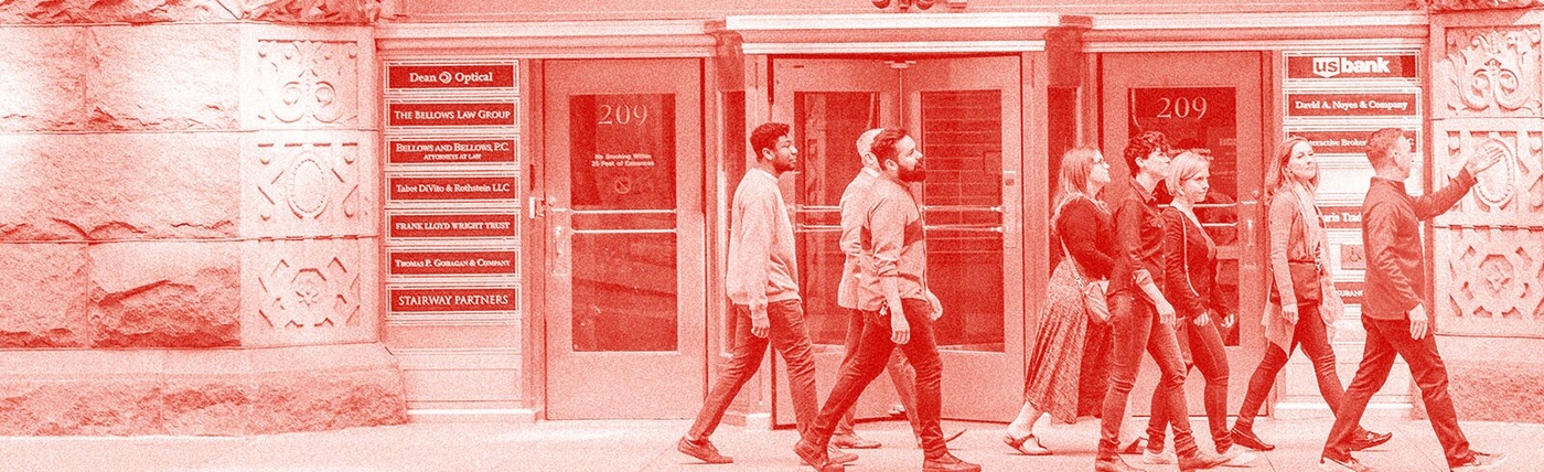 People walking down a city street on a tour. The photo has a red overlay. 