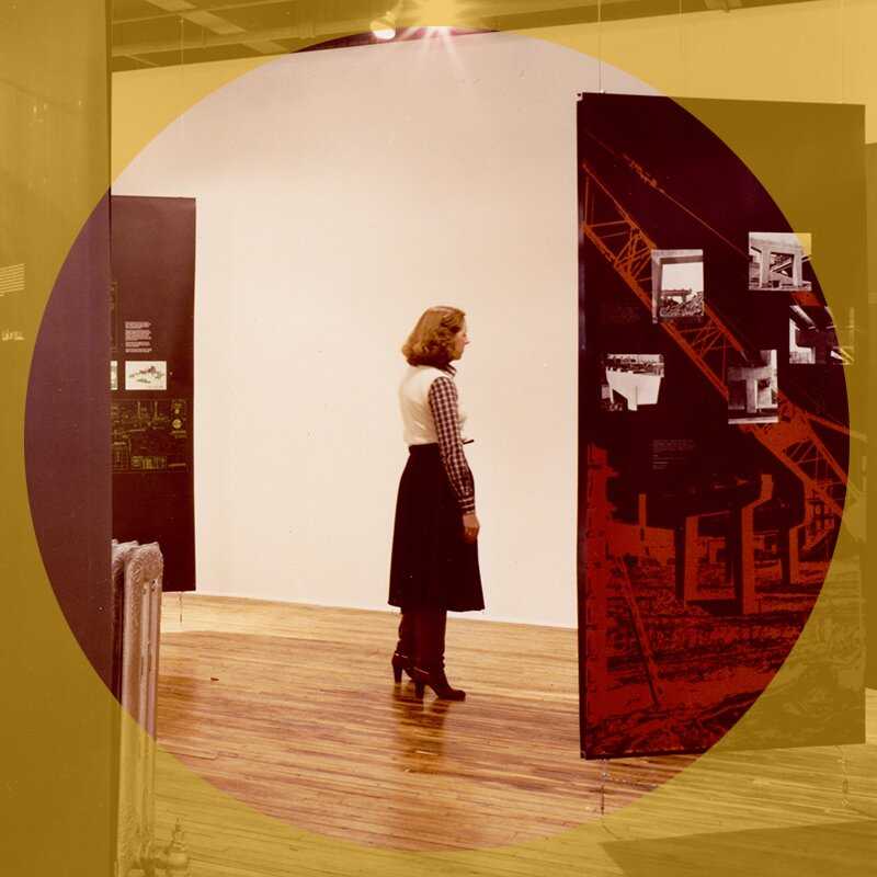 A woman stands in the middle of a gallery reading a panel. 