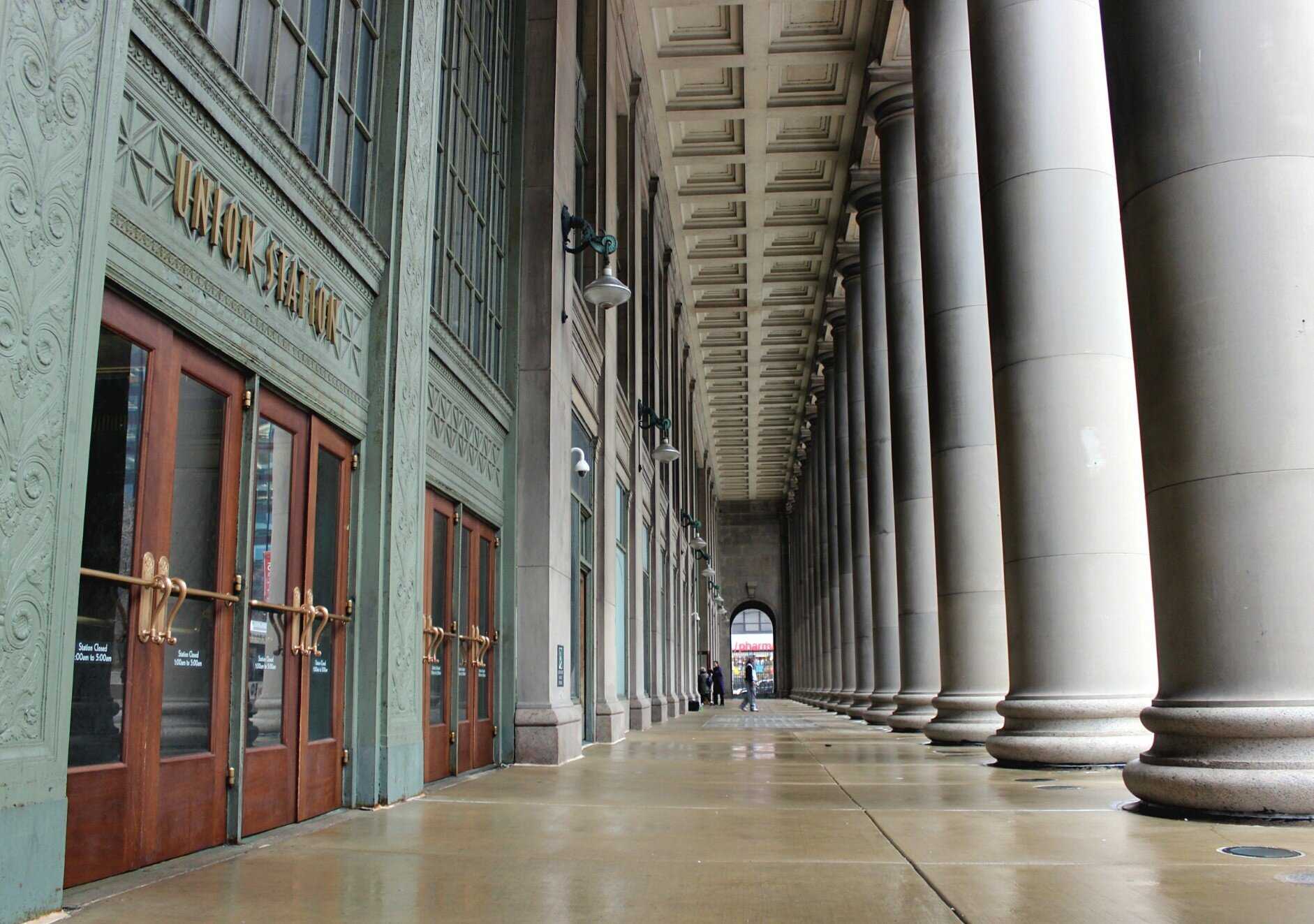 Exterior shot of Union station featuring the wooden doors surrounded by ornate green walls on the left and large white columns to the right