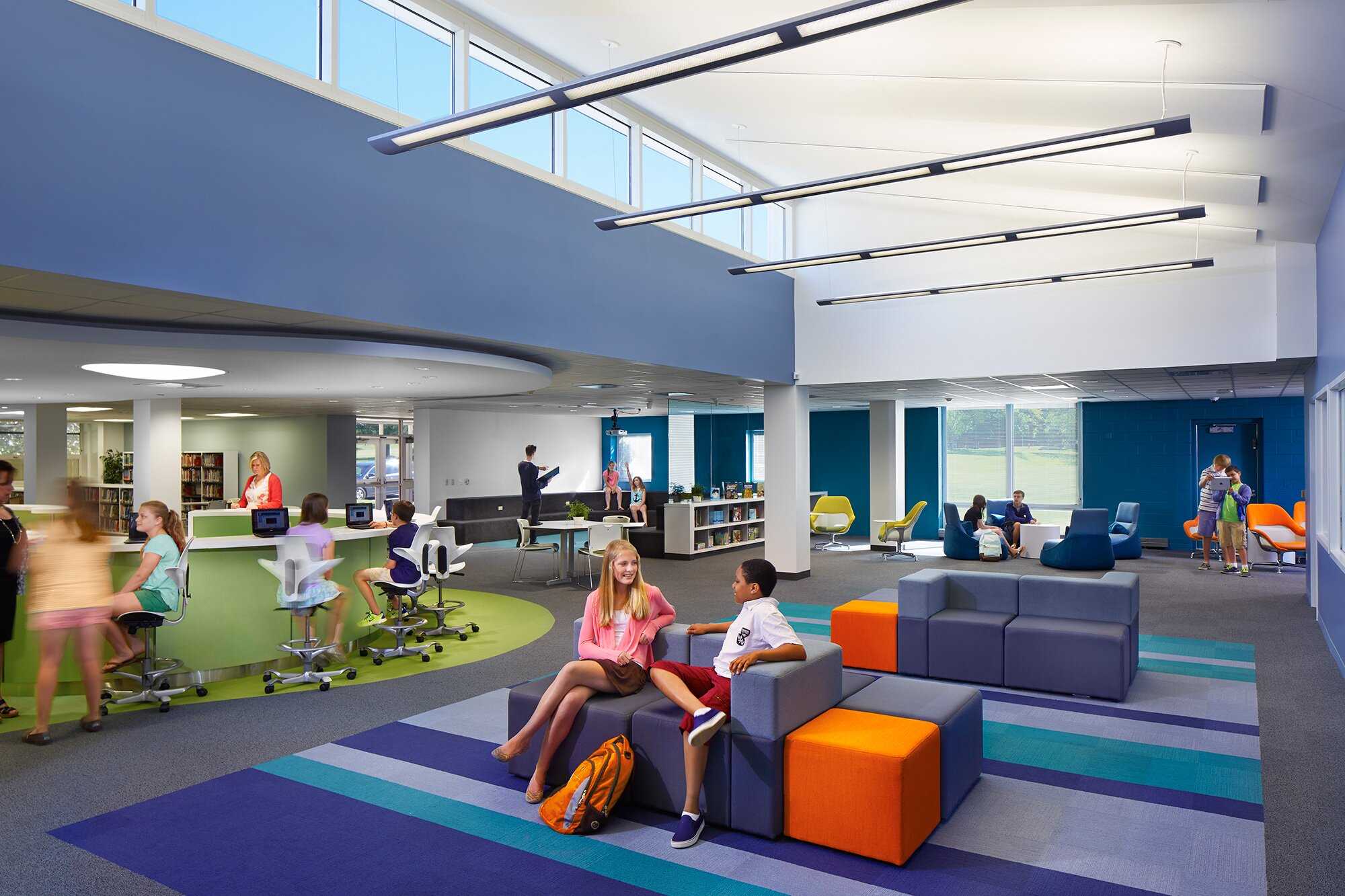 Inside a modern designed school with bold colors and kids sitting around cubes and chairs