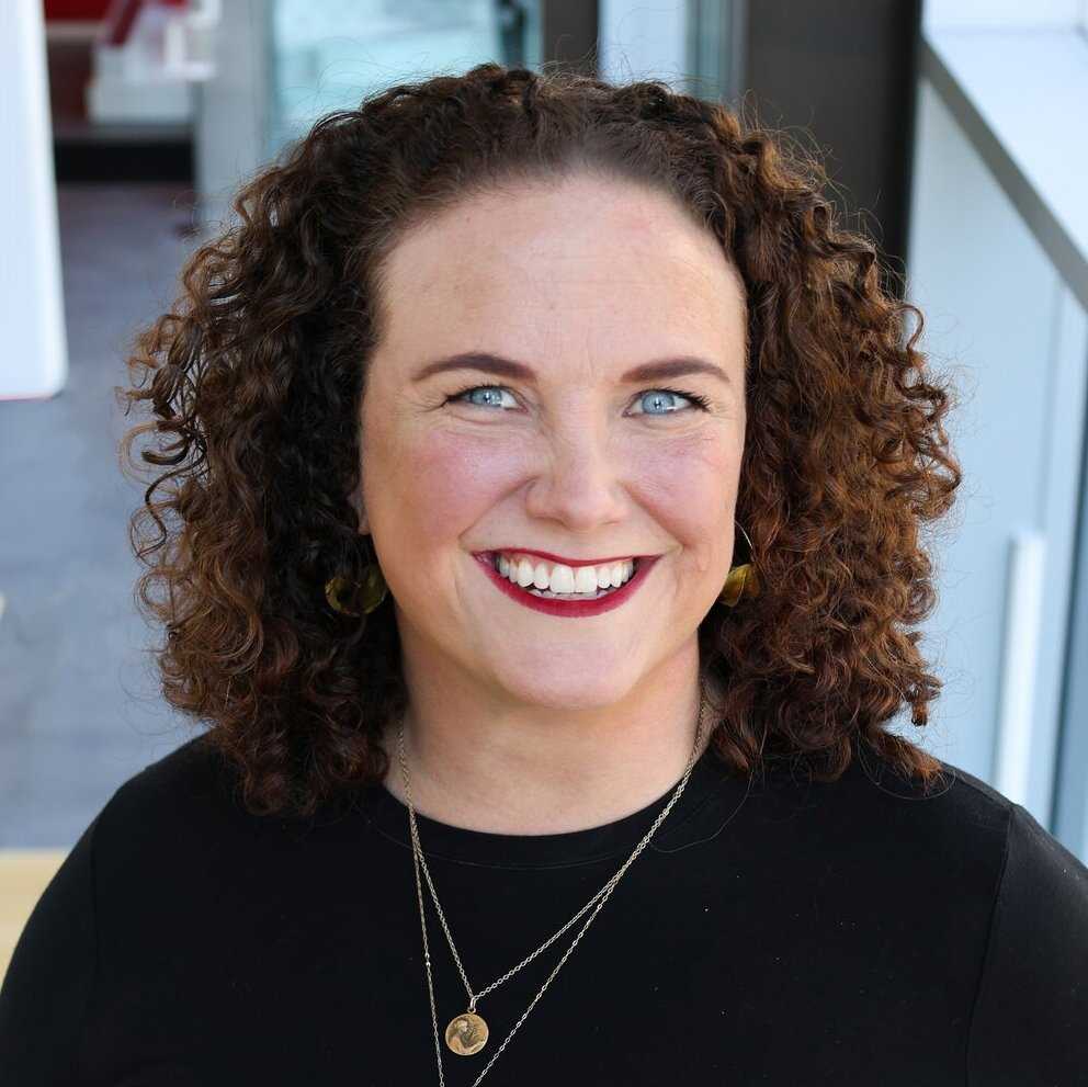 Caucasian woman with curly brown hair in a black top