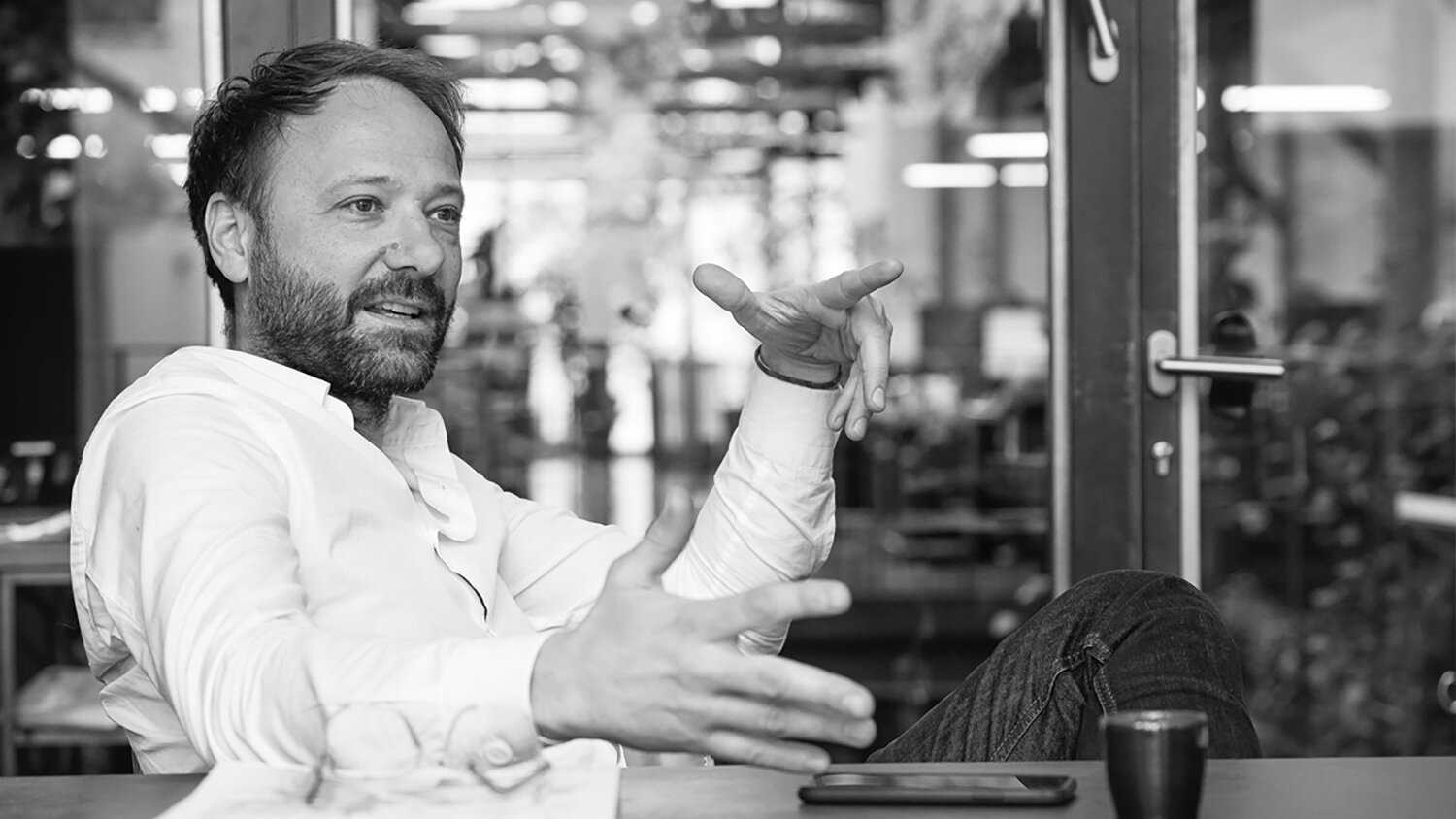 Black and white of a caucasian man seated and in mid conversation