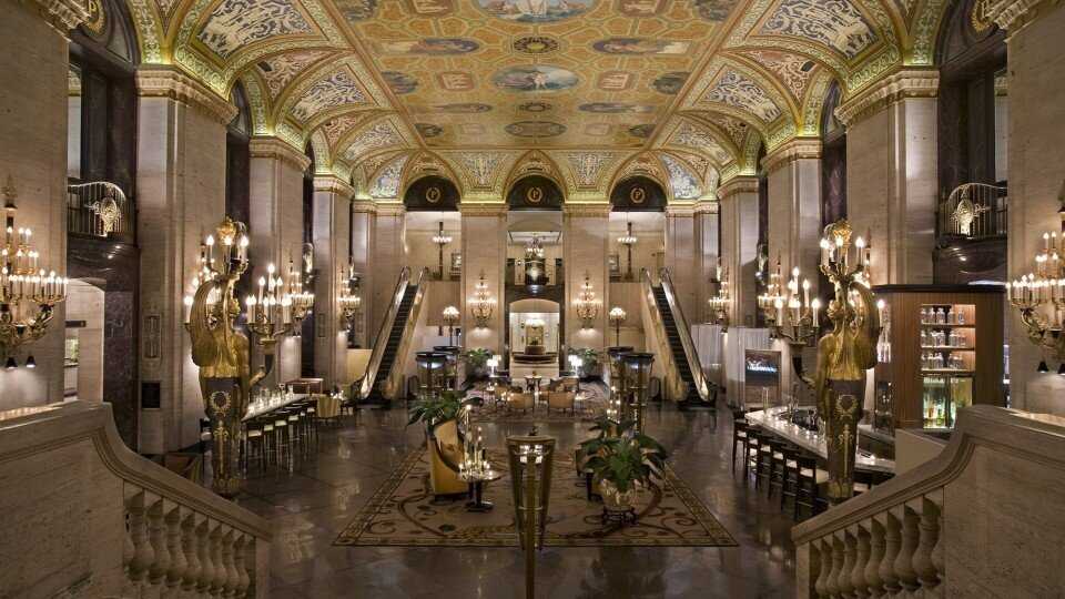 Hotel interior showing a painted ceiling, a staircase, and golden light fixtures