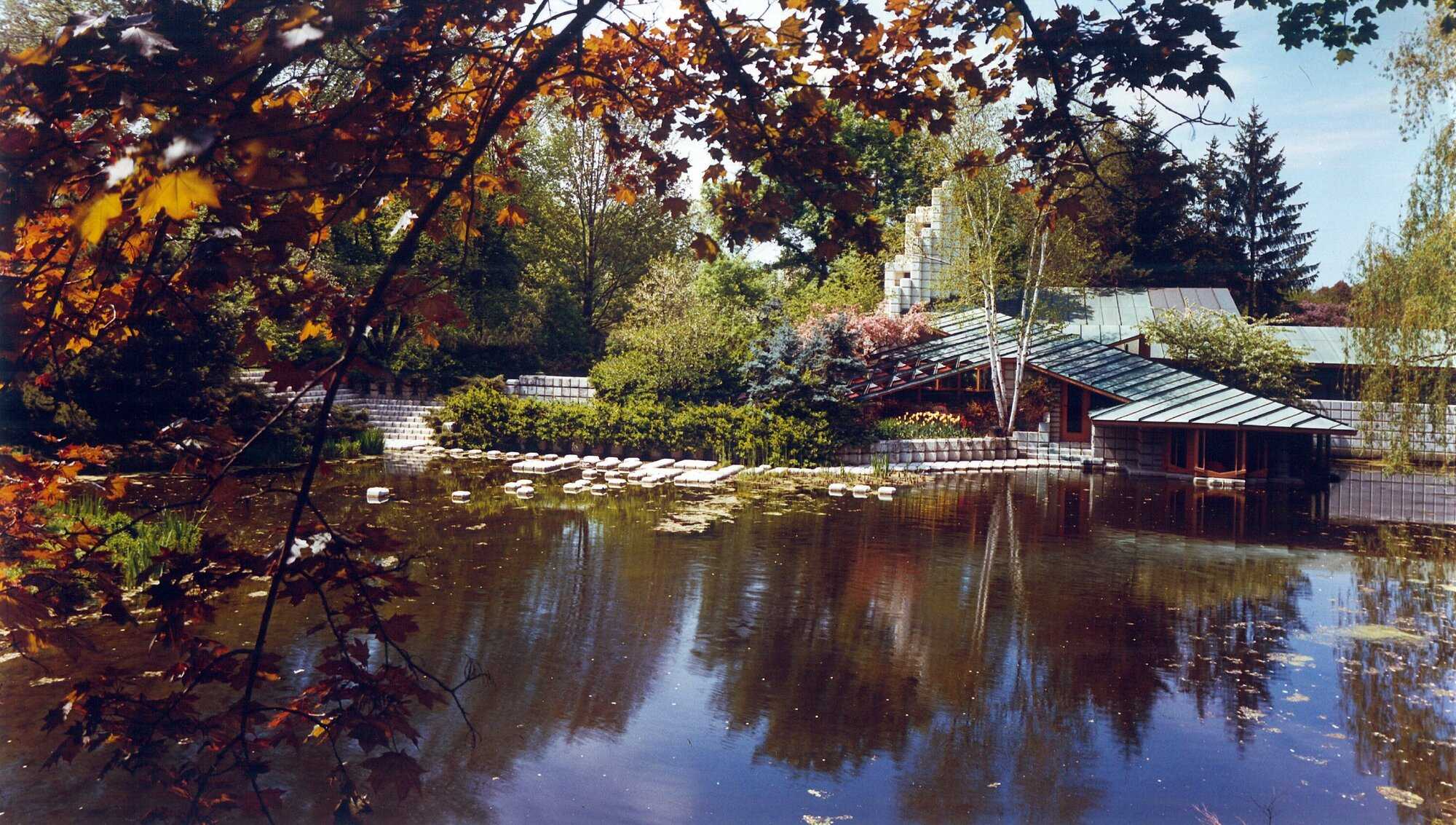 An image of a mid-century modern house on a lake surrounded by trees