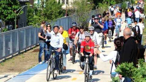 Group of bikers with helmets riding on elevated bike path with in the daytime.