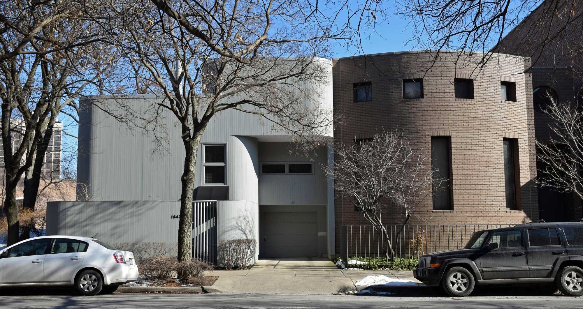 Exterior view of modern home with curved walls and flat roof.