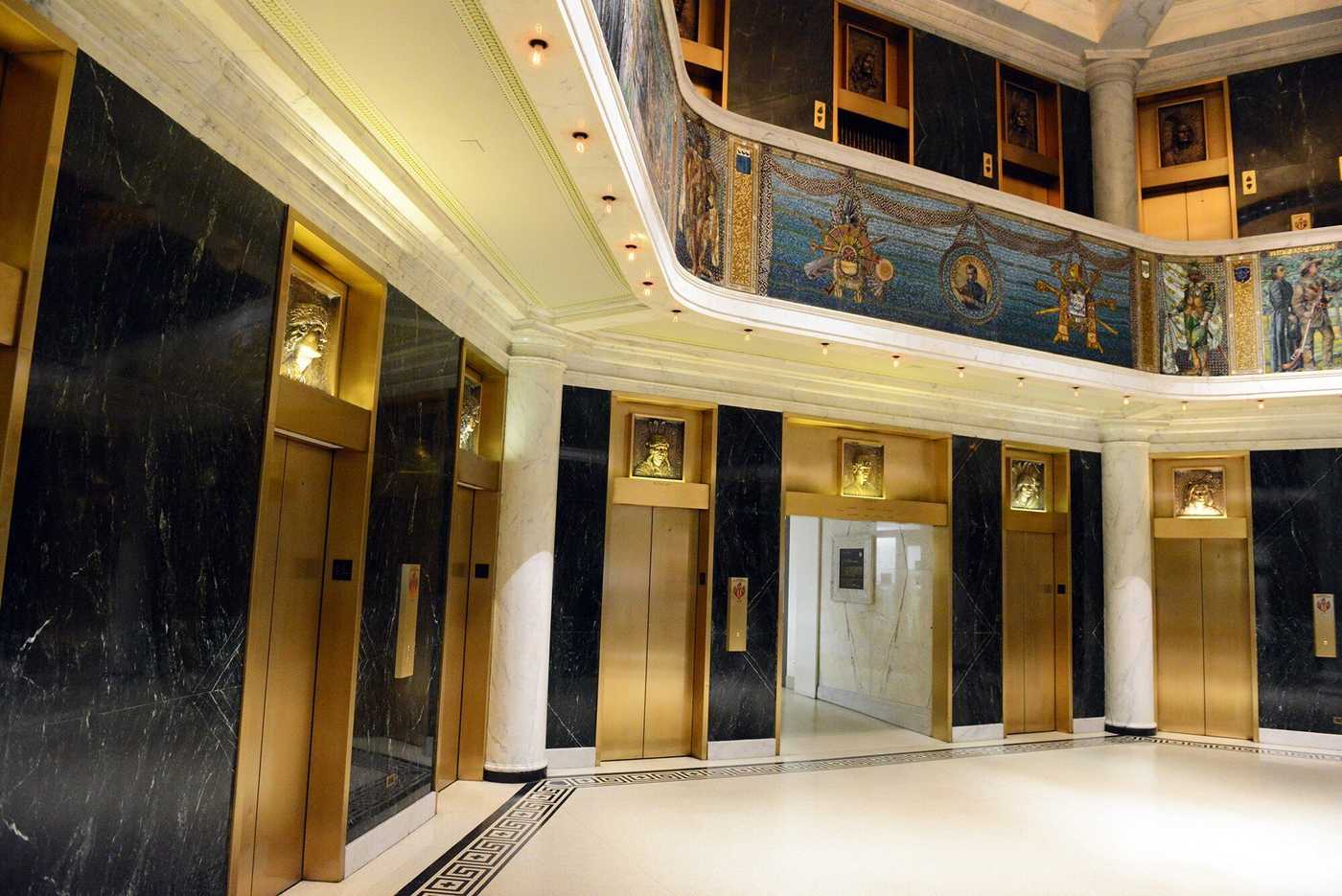 Interior building lobby with elevators and mural.