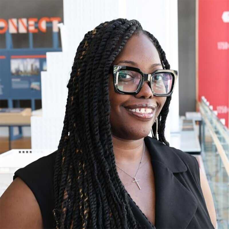 Headshot of a young black female professional with black framed glasses