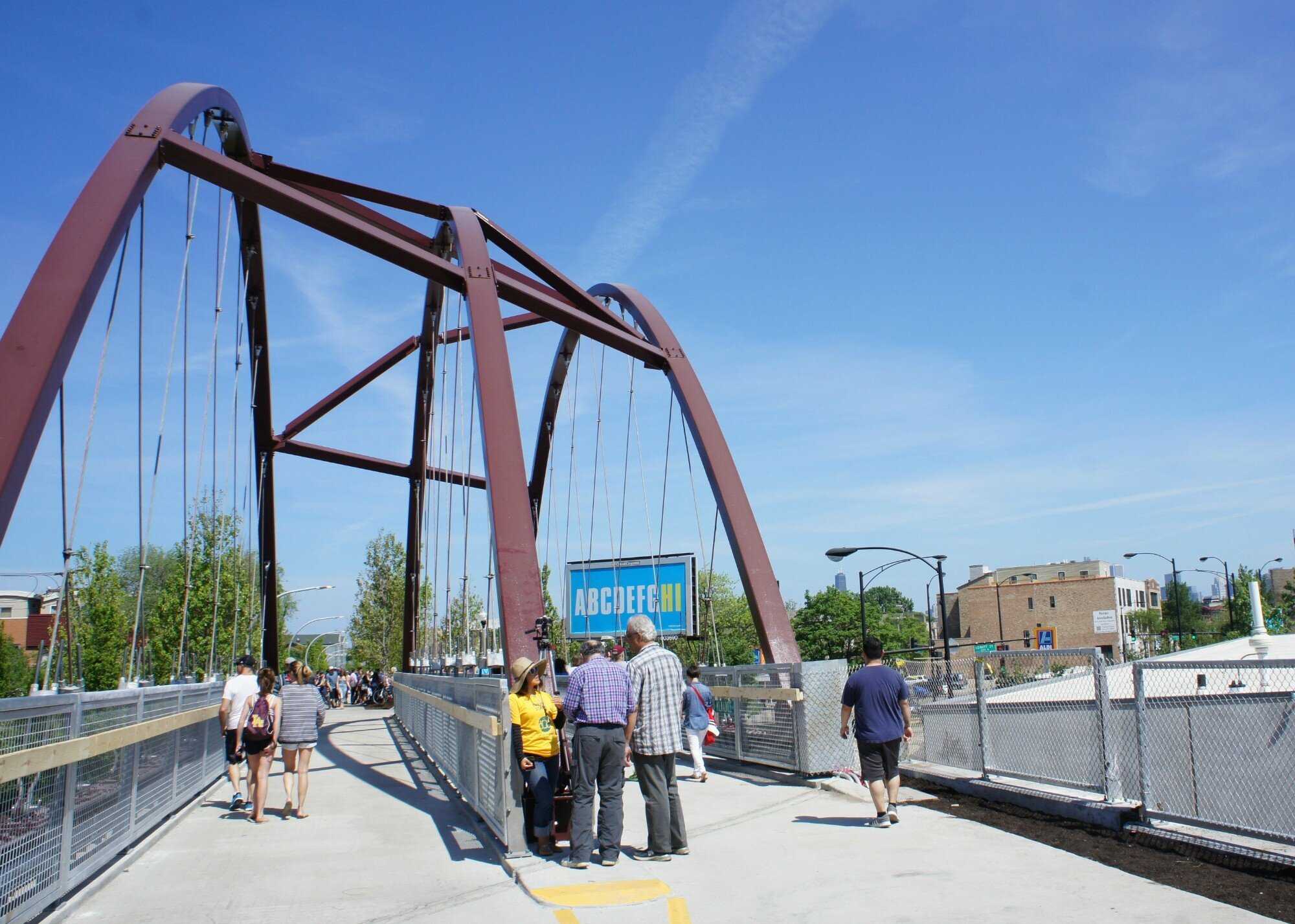 Group of people standing and walking under a bridge on a pedestrian path. 