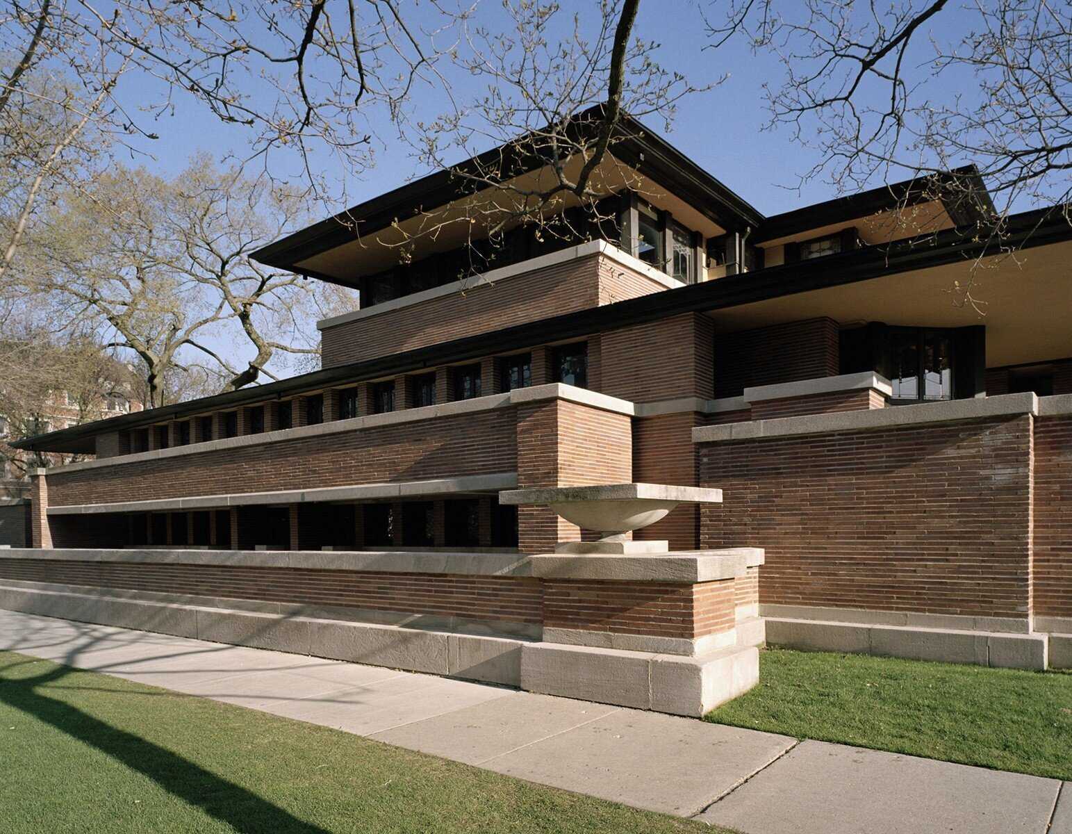 Exterior view of the Robie House by Frank Lloyd Wright, showcasing Prairie School architecture with horizontal lines, overhanging eaves, and expansive windows.