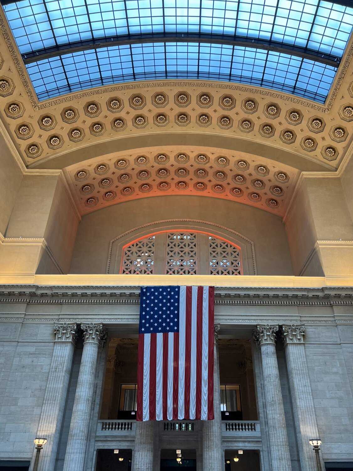 Photo of an American flag hanging in the Great Hall of Union Station with an arched ceiling above