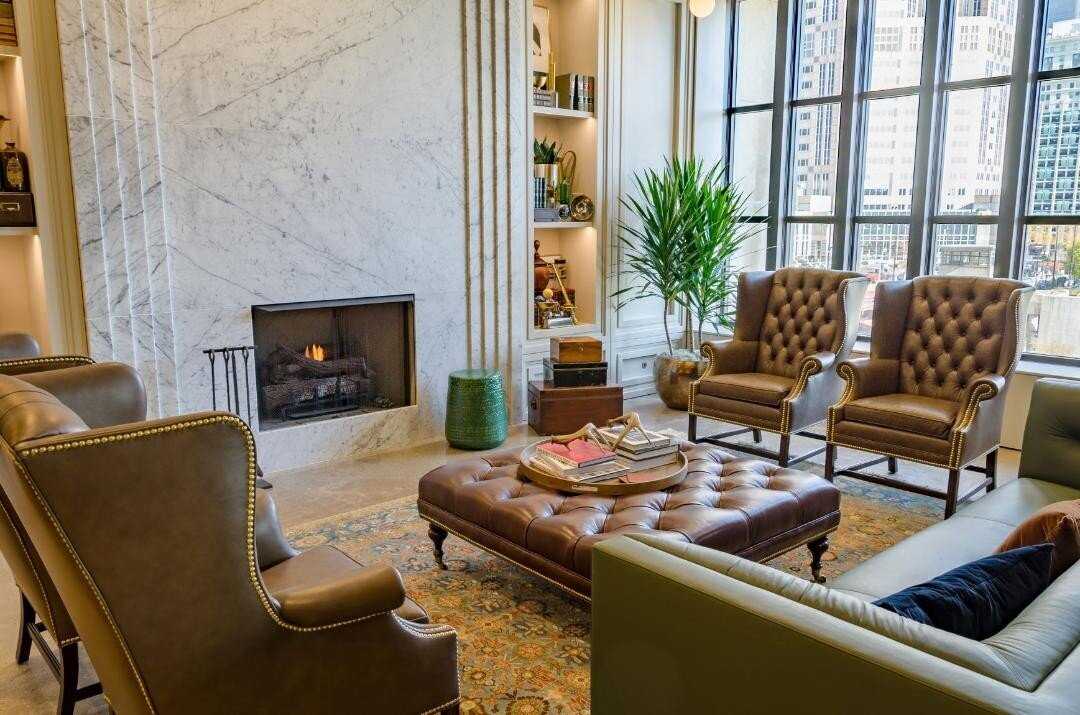 lounge with white marble fireplace and tufted brown leather chairs