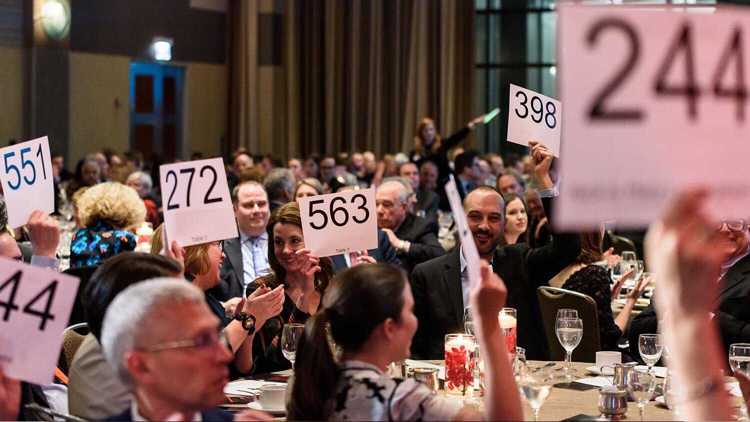 An auction event with people seated and putting up auction bids