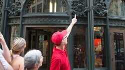 A person in a red tshirt talks to a grey haired person who is facing away from the camera