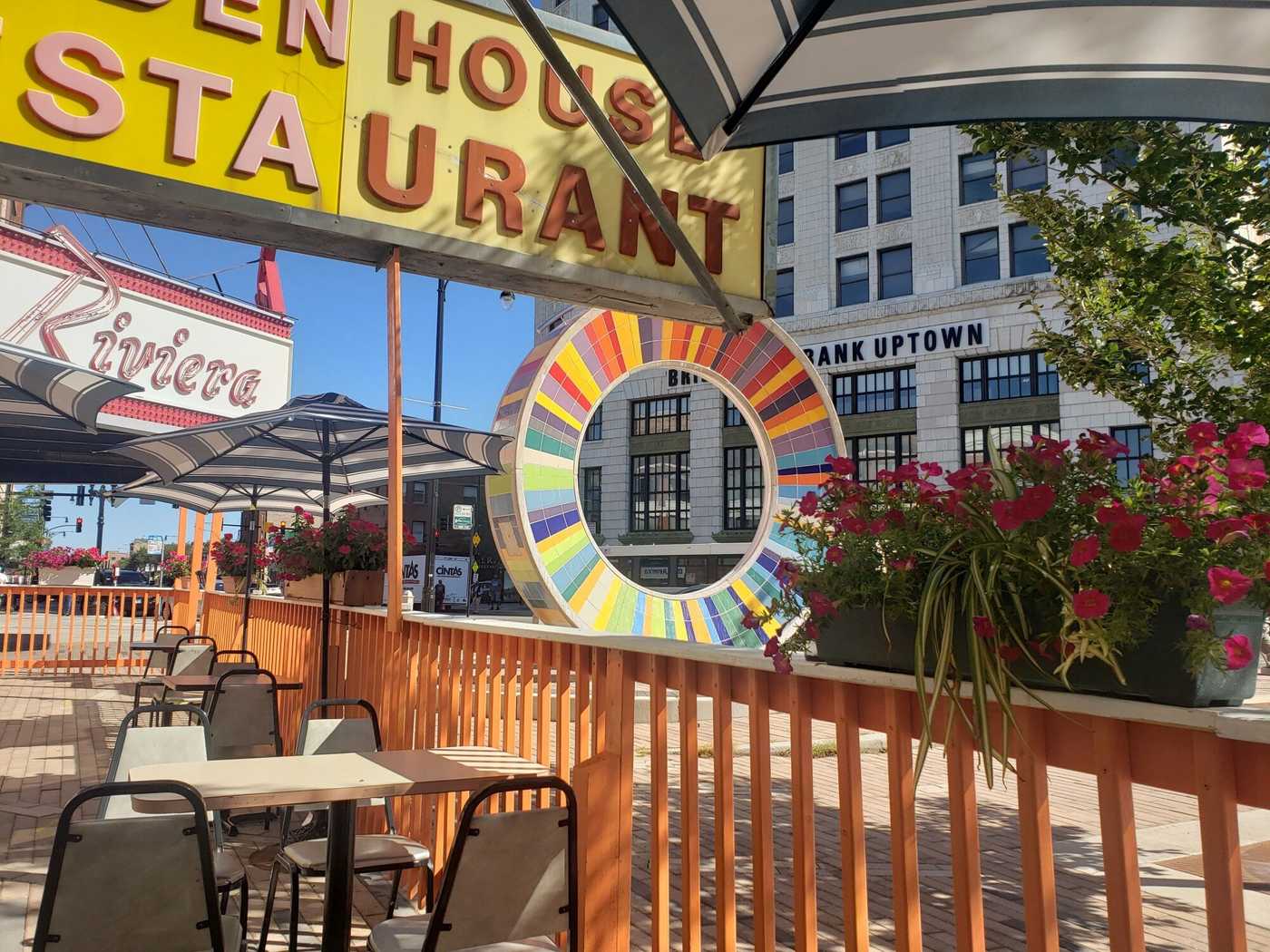 Large colorful wheel on city street with bank in background.