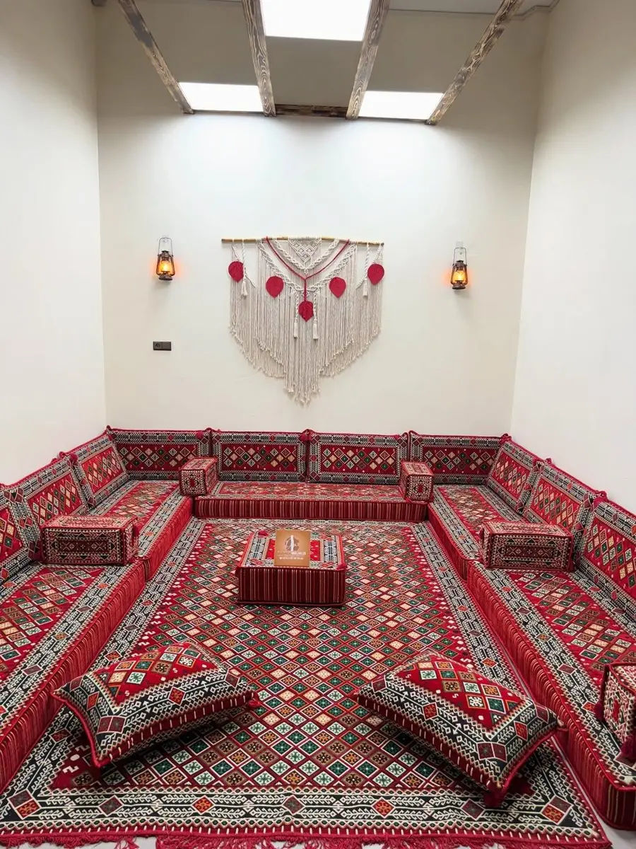 مجلس صحراوي من صنع الداخلة مجالس بحشايا ومساند حمراء بزخارف صحراوية حول زربية منسجمة
