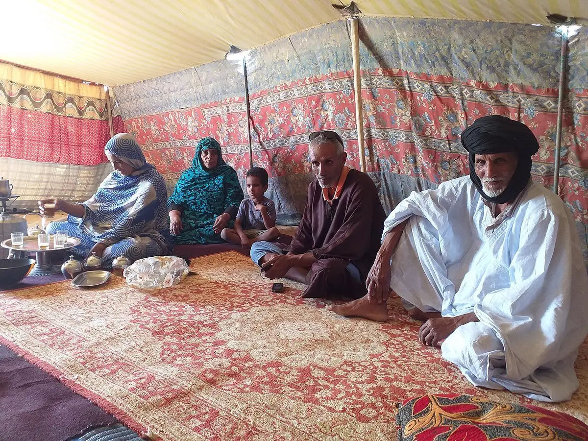 خيمة تقليدية في موريتانيا يجلس فيها أفراد على زرابي مفروشة على الأرض حول صينية الشاي