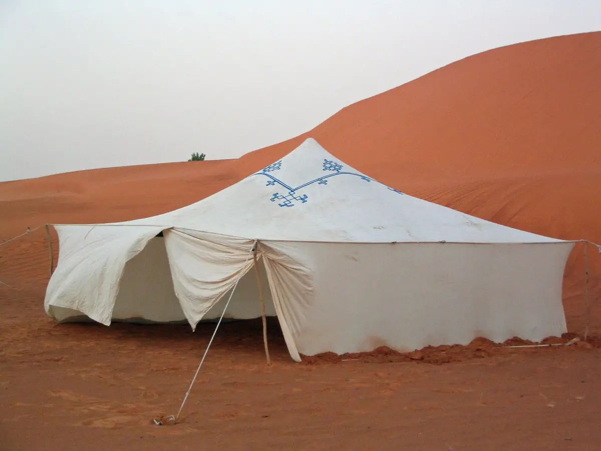 White traditional tent pitched on red sand dunes