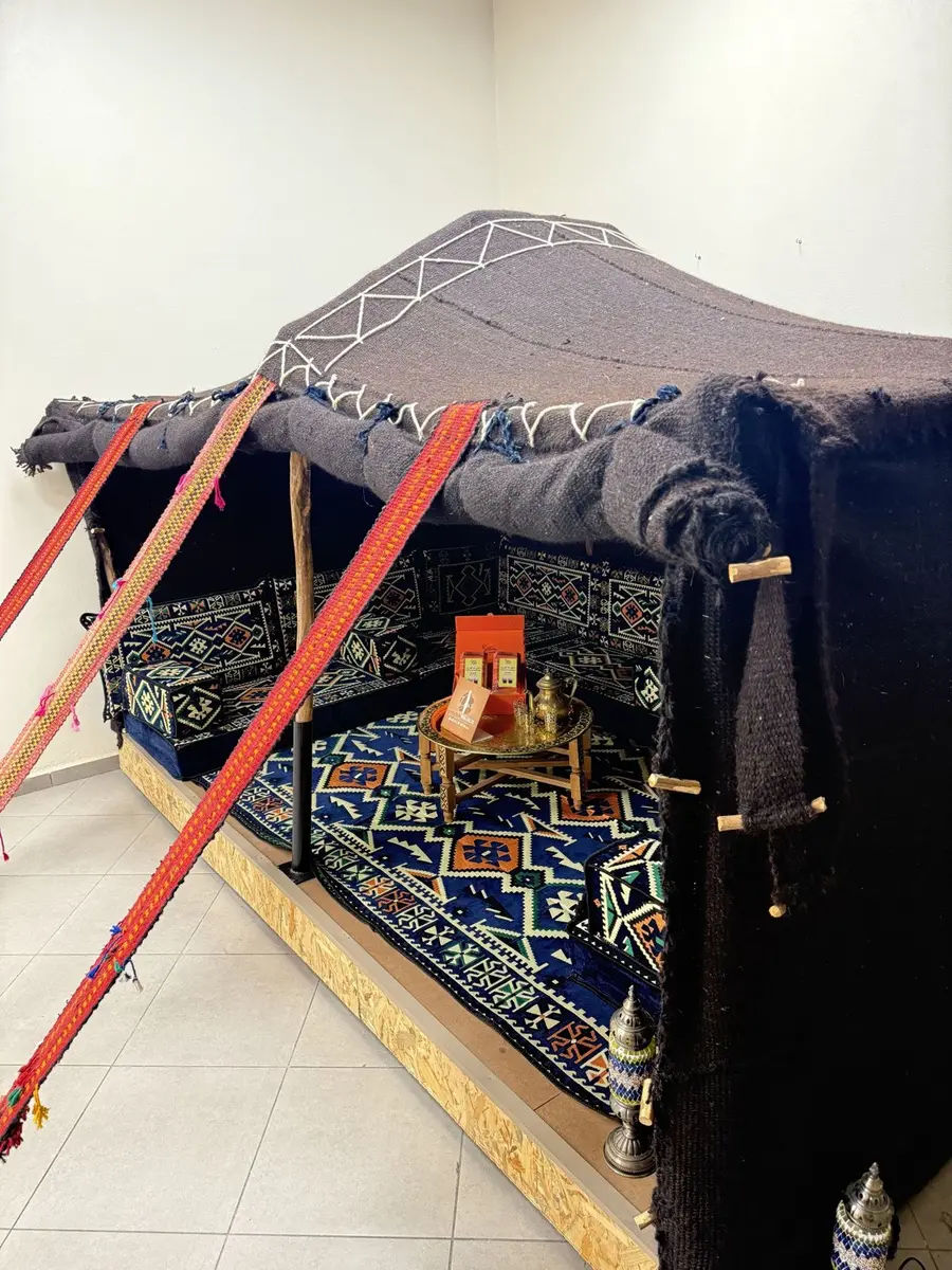 Sahrawi majlis with geometric patterns inside a goat-hair tent, around a low tea table