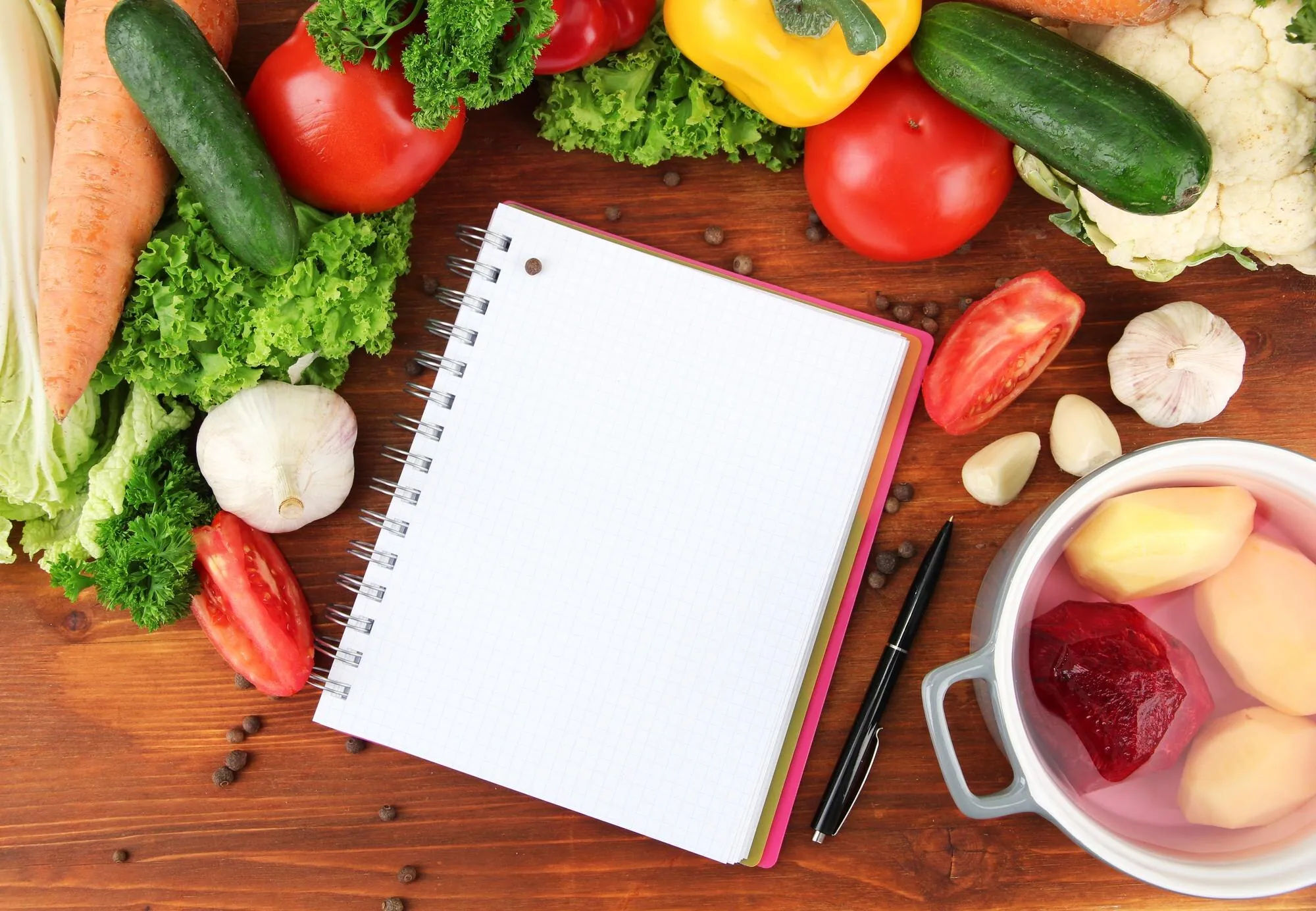 Notebook surrounded by vegetables for meal planning
