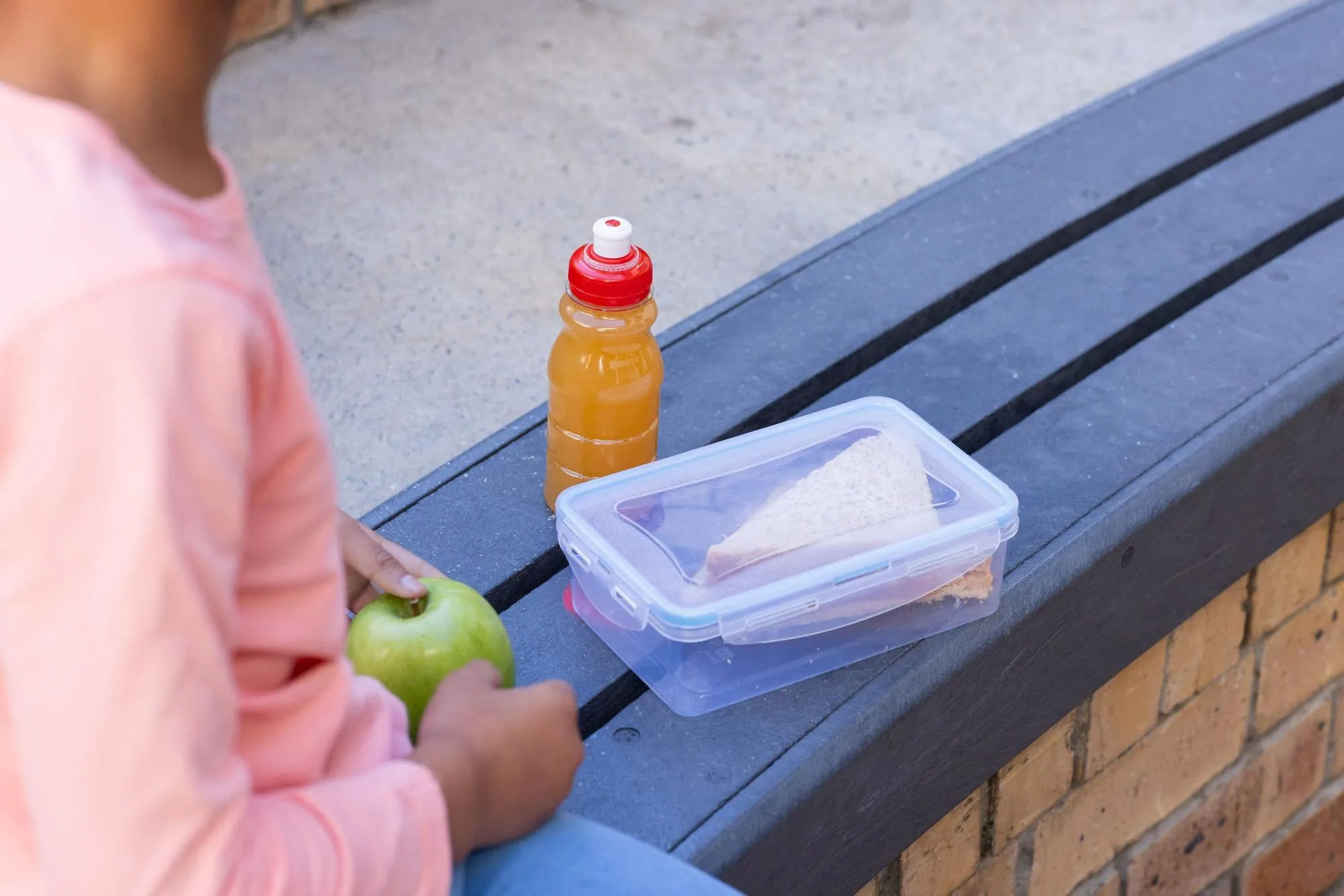 Niño comiendo un sándwich y una manzana empaquetados durante el día escolar