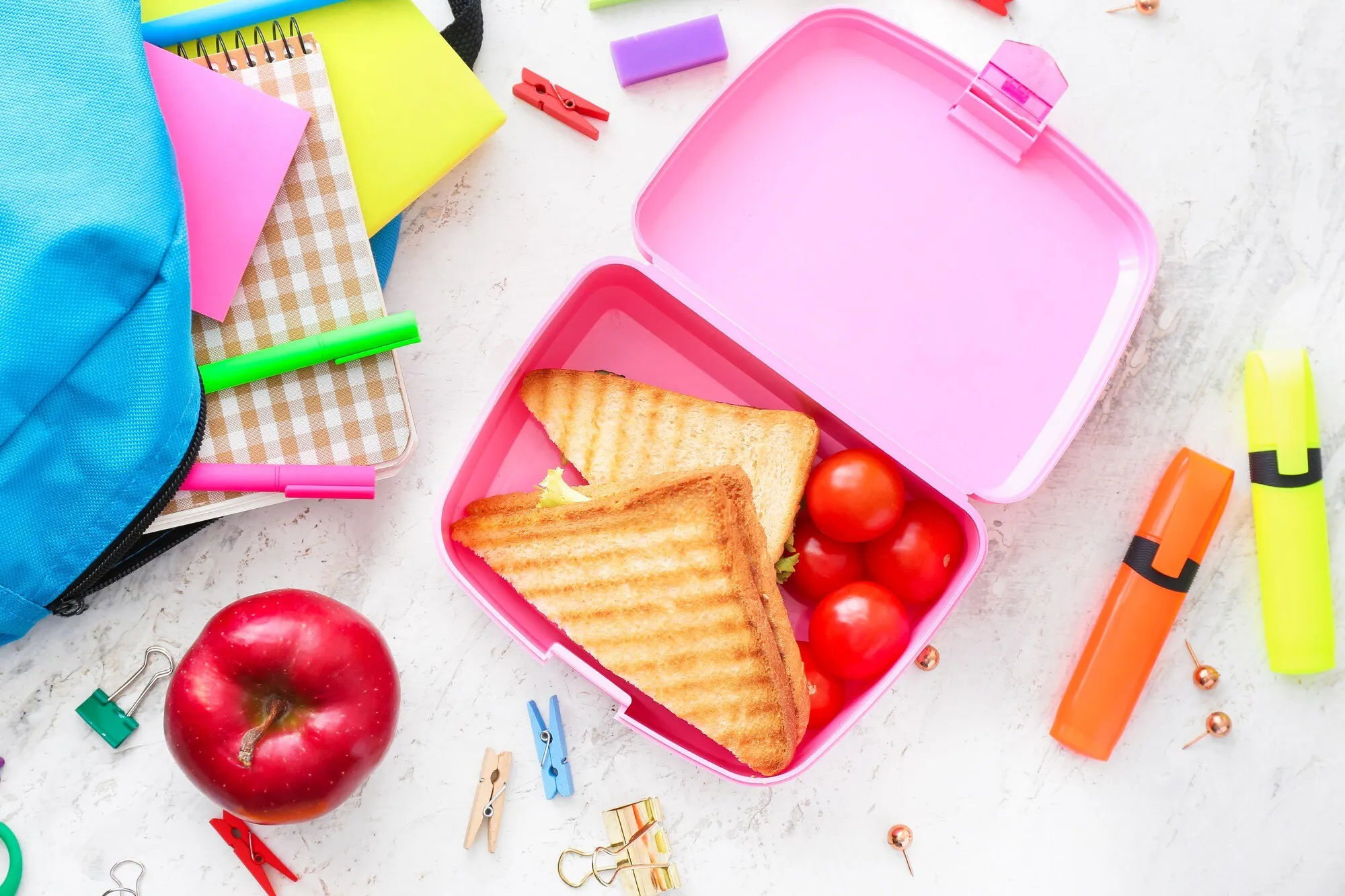 Sándwiches, tomates y una manzana empaquetados en una lonchera escolar