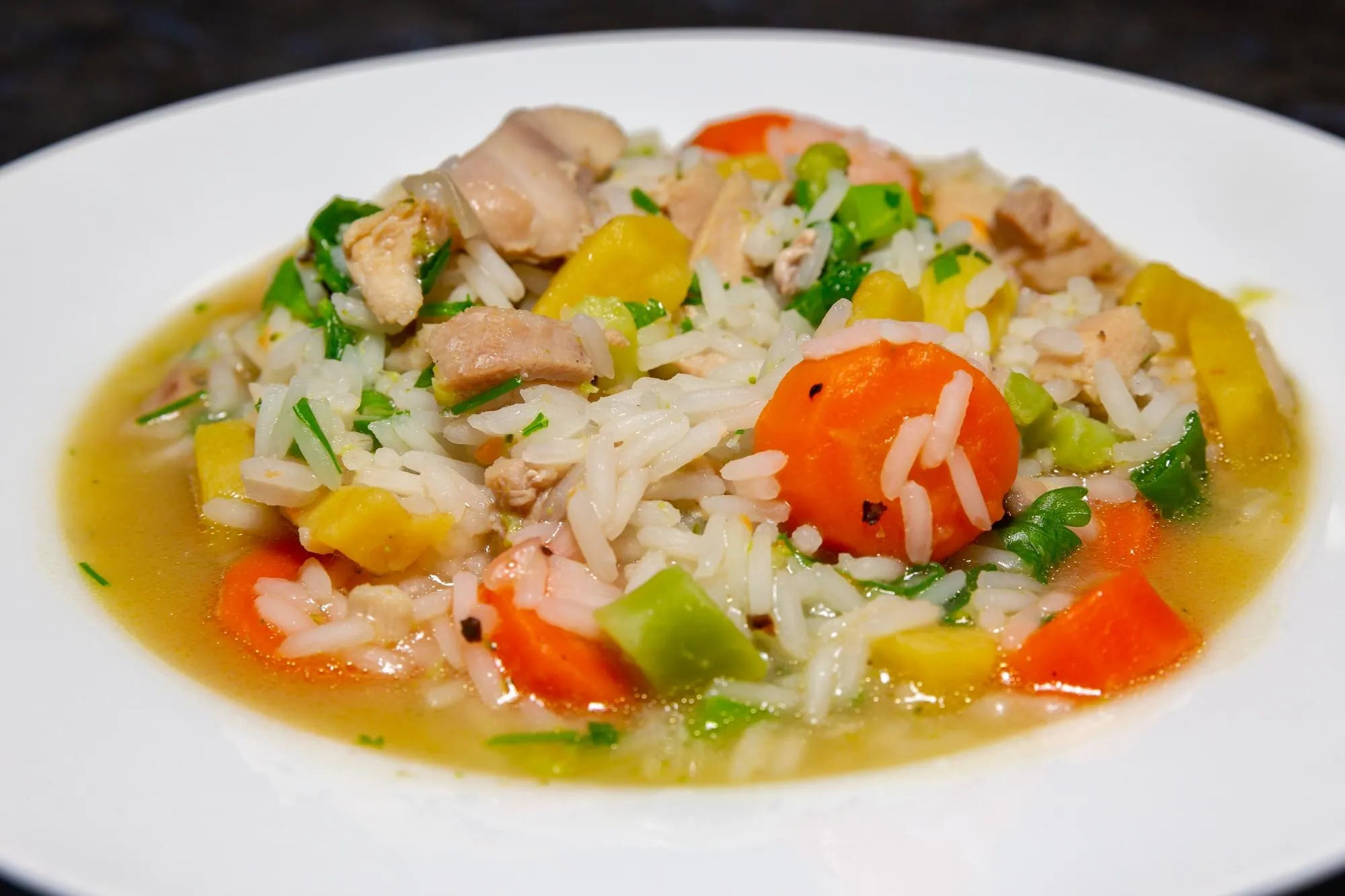 Sopa de pollo y arroz con zanahoria, pimiento y hierbas