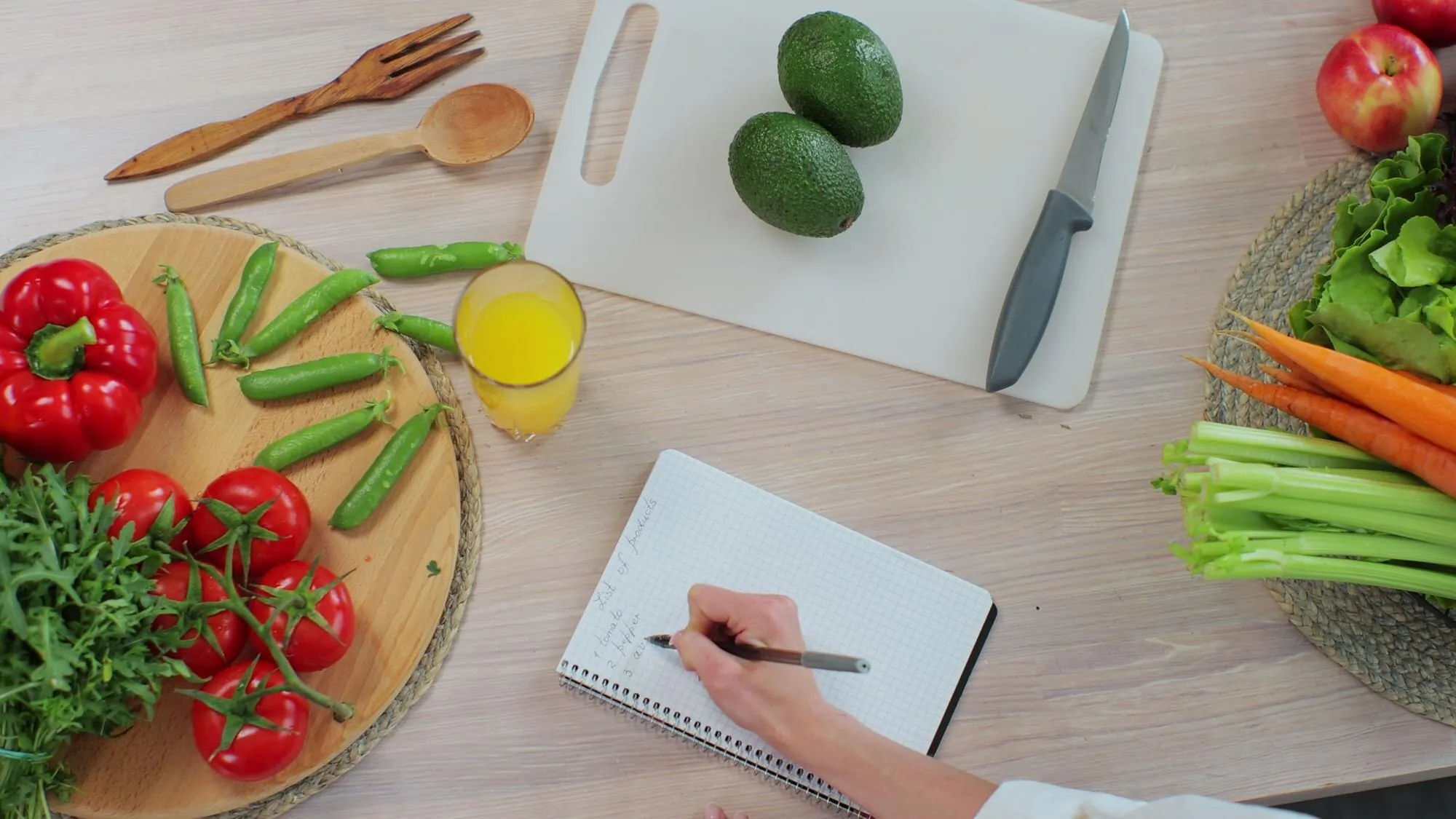 Writing a grocery list beside fresh vegetables