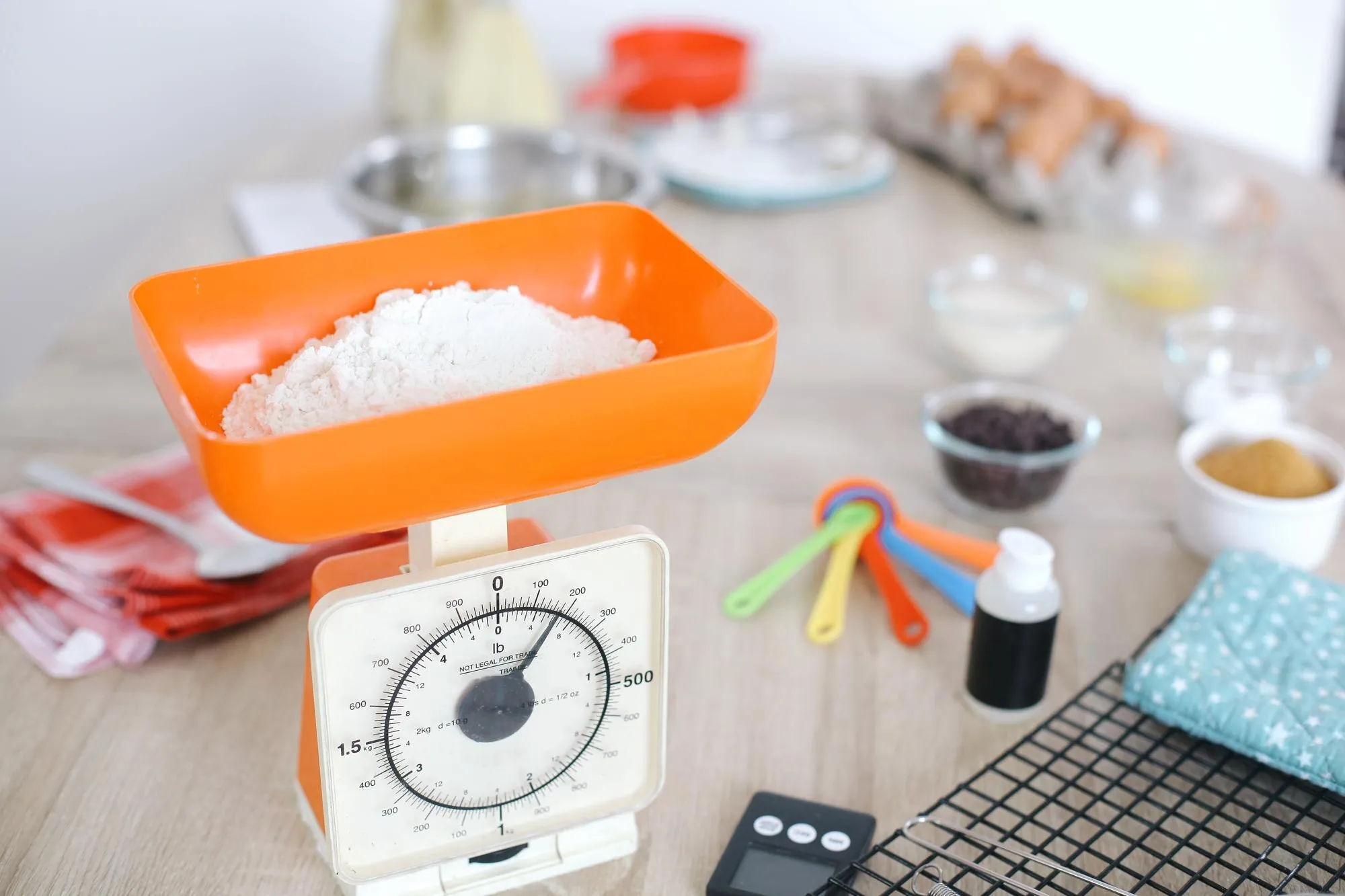 Farinha em uma balança de cozinha ao lado de utensílios de medição para converter unidades com cuidado