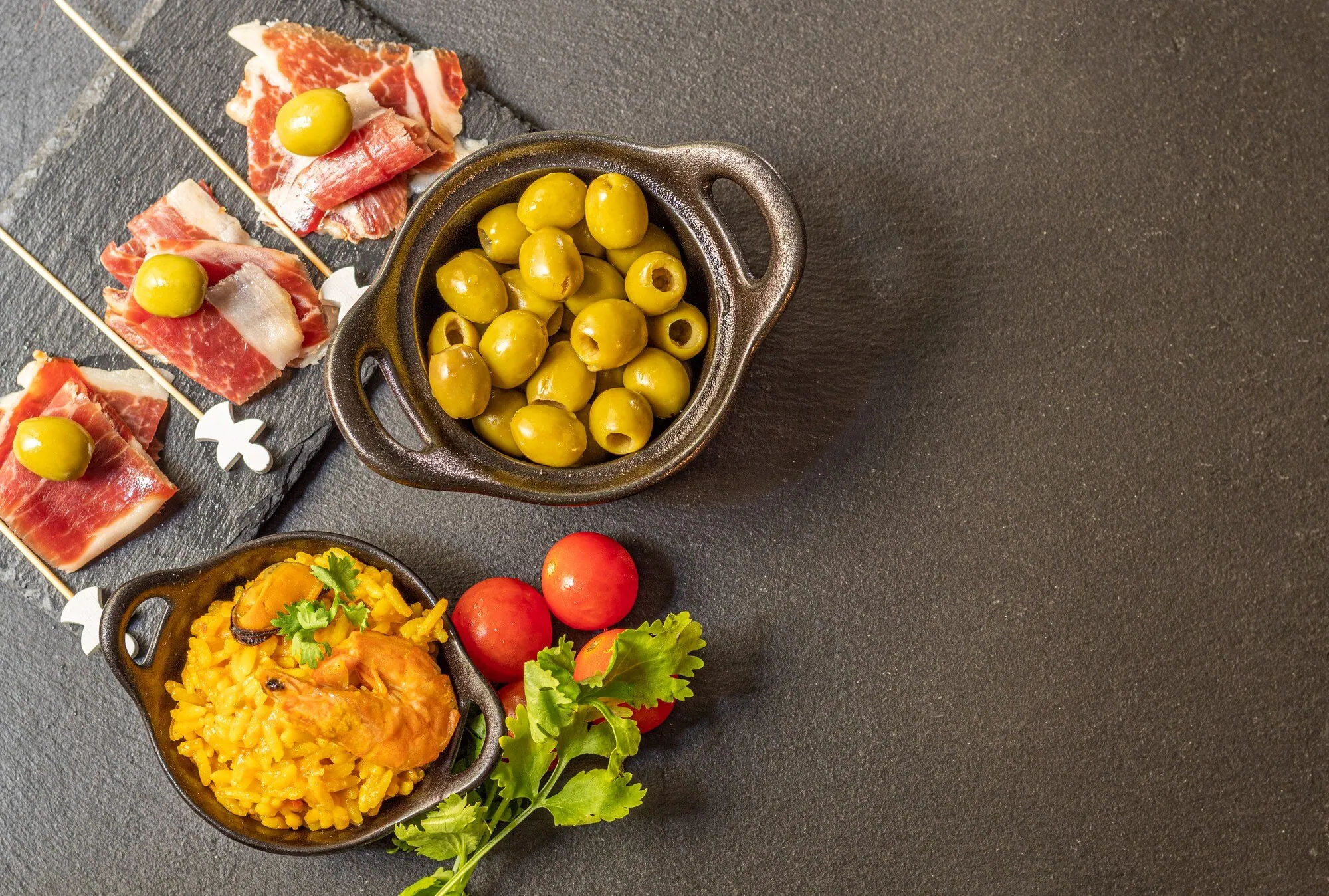 Spanische Tapas mit Oliven und Schinken auf Schieferplatten