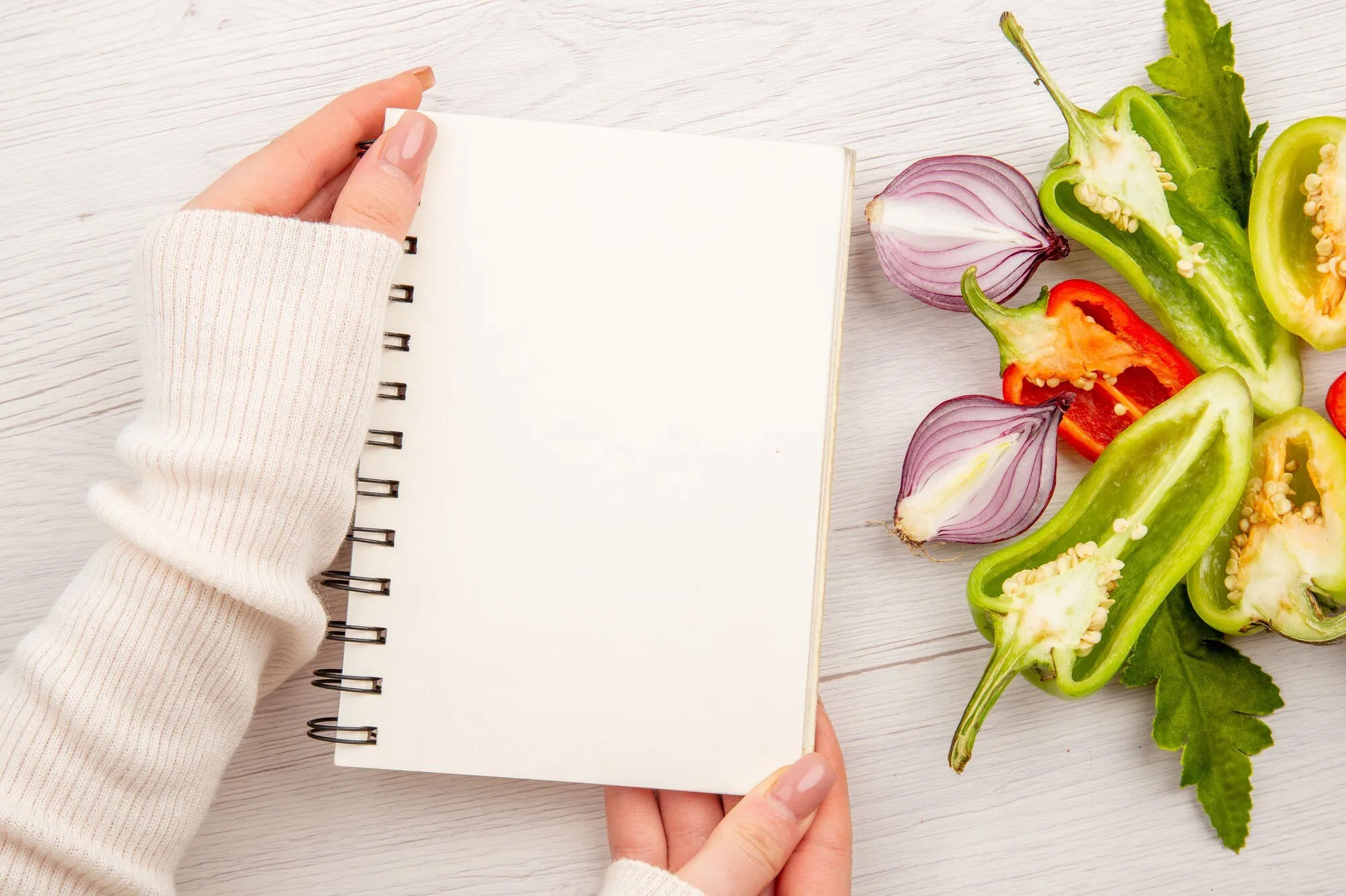 Blank planning notebook beside vegetables for turning saved recipes into actual meals
