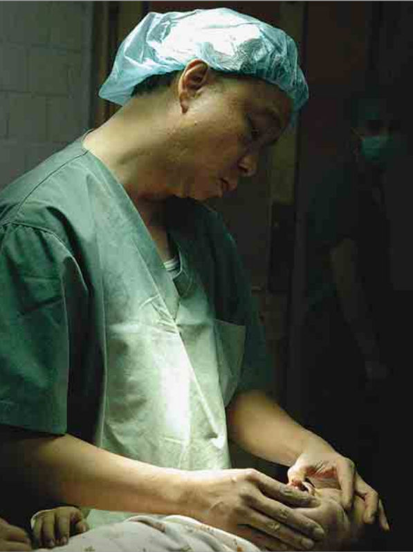 Black and white photo of a man wearing glasses and a cap holding a baby