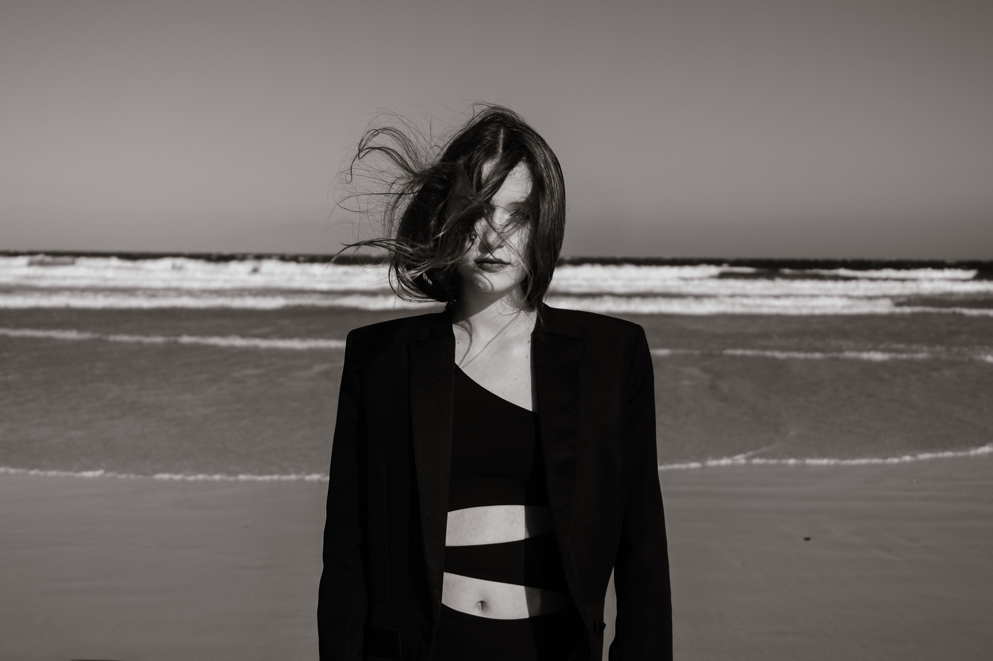 Woman in a black blazer on a windswept beach