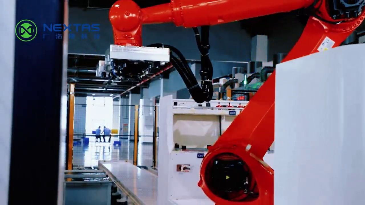 Robot carrying a metal pallet beside a NEXTAS machine enclosure