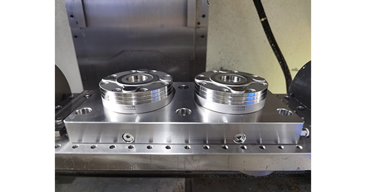 Two round zero-point receivers mounted on a rectangular plate inside a CNC machine