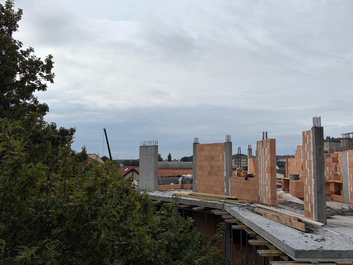Murowane ściany i betonowe słupy powstającej kondygnacji budynku