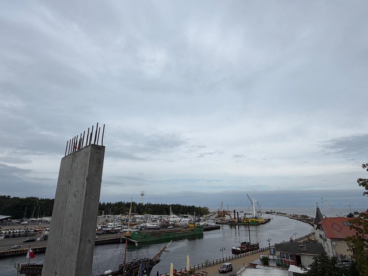 Widok na marinę w Ustce obok betonowego słupa konstrukcji budynku