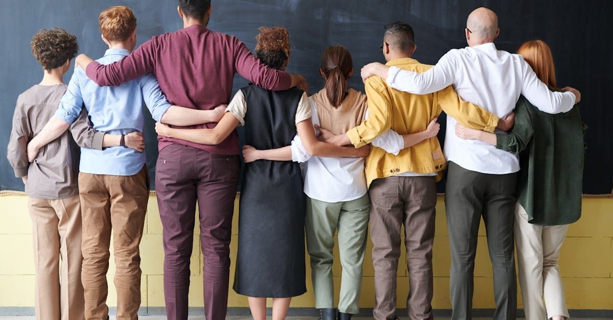View of the back side of a group of people hugging and supporting each other.