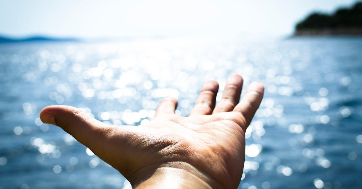 Hand reaching out to the horizon at the edge of the ocean.