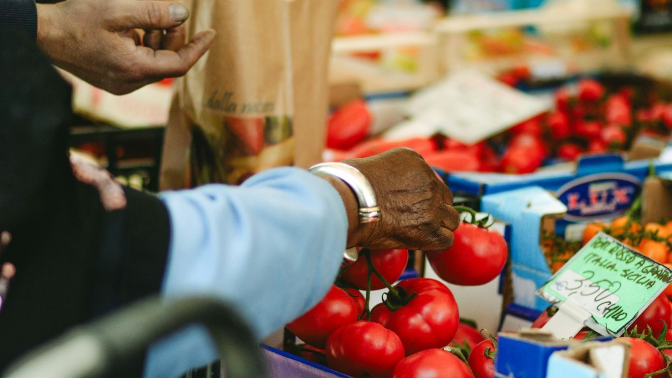 a person picking out tomatoes from a produce table