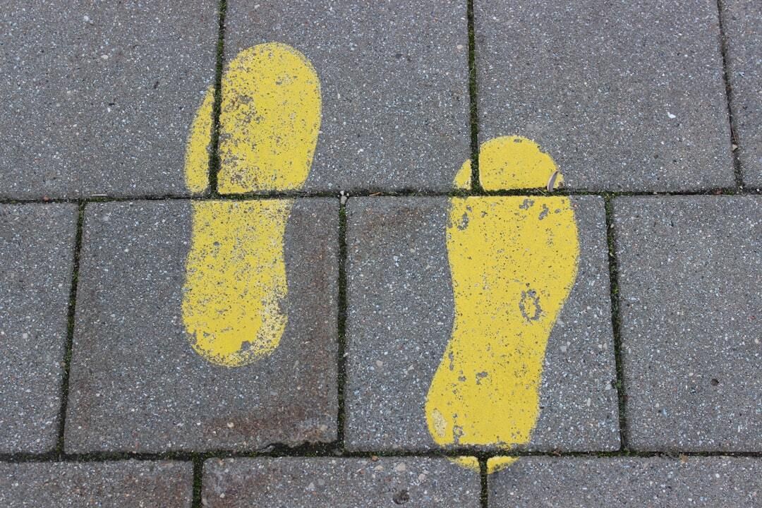 Image of two yellow foot prints on concrete paver walkway.